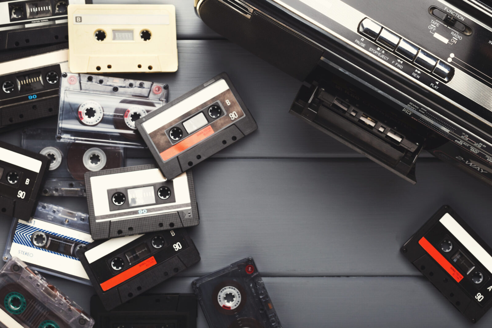 Heap Of Vintage Audio Cassettes And Tape Recorder At Gray Background